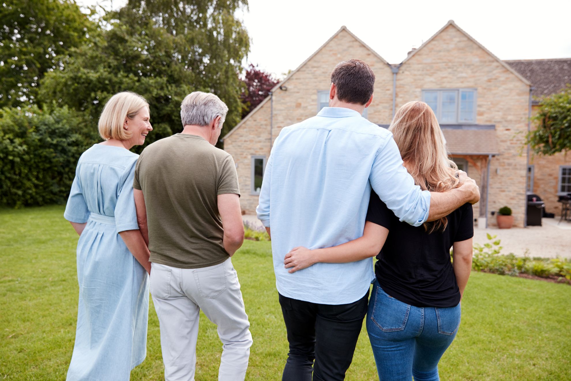 Three generations of a family looking up at a stone-clad house